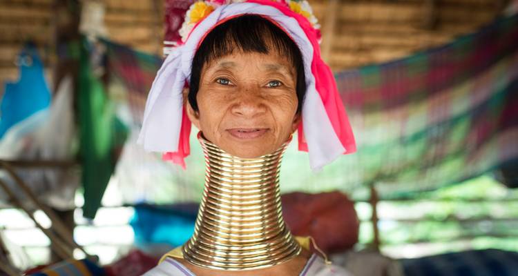 Femme portant des anneaux de cou traditionnels, souriante.