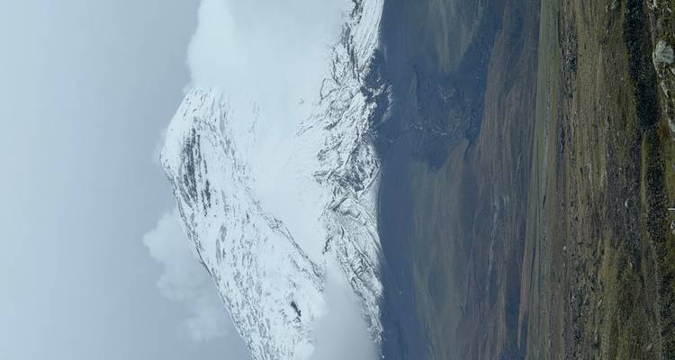Pico de montaña cubierto de nieve bajo un cielo nublado.