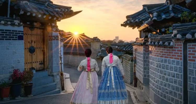Traditionele Koreaanse straatscène met vrouwen in hanbok bij zonsondergang.