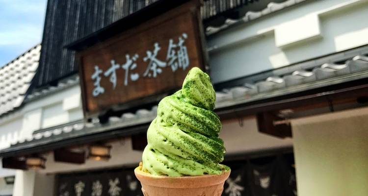 Close-up van een matcha ijshoorntje voor een traditioneel gebouw.