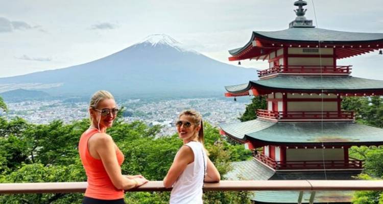 Dos personas disfrutando de la vista del Monte Fuji con una pagoda.