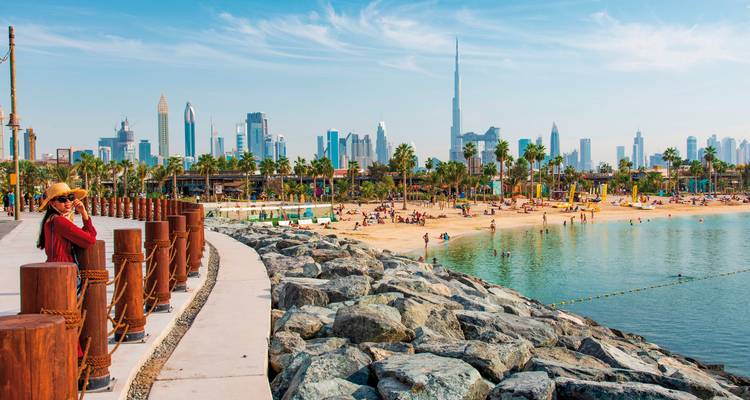 Strandfront in Dubai mit Menschen, die die Sonne genießen.