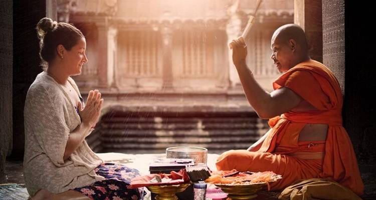 Moine bouddhiste donnant une bénédiction à une femme dans un temple.