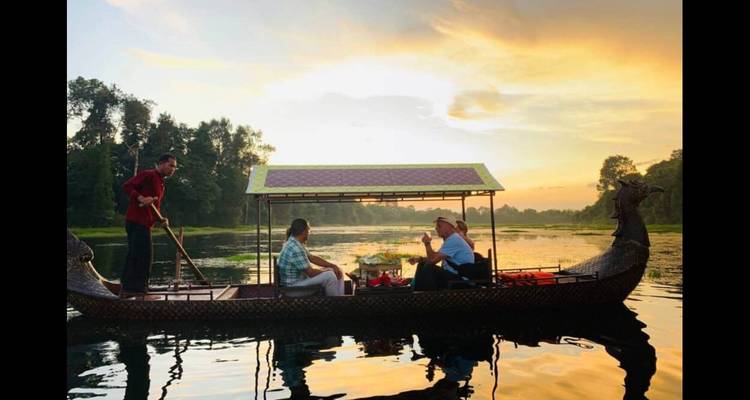 Small group enjoying a boat tour on a calm river at sunset.