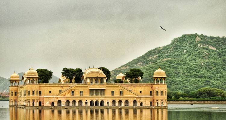 Palais historique sur un lac avec des montagnes en arrière-plan.