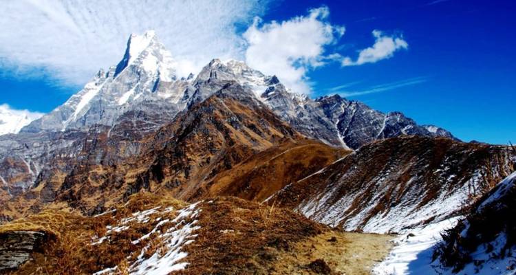 Snow-dusted mountains with a winding path leading towards them.