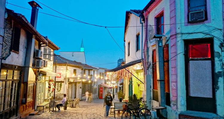 Des gens marchant dans une rue pittoresque avec des bâtiments colorés.