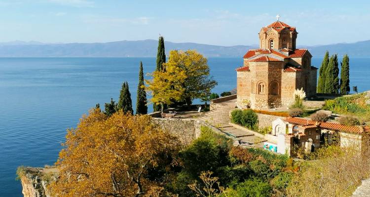 Une église historique perchée sur une falaise surplombant une grande étendue d'eau.