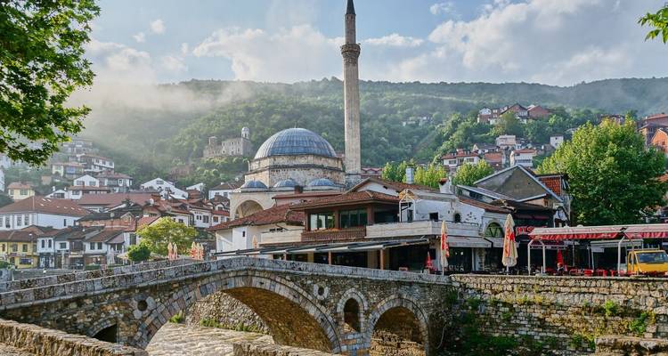 Une mosquée et un pont de pierre avec en toile de fond des collines verdoyantes luxuriantes.
