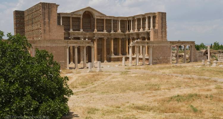 Fachada bien conservada del antiguo gimnasio de Sardis con columnas y muros de ladrillo bajo cielo azul.