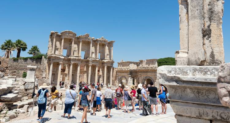 Reisegruppe versammelt sich vor den Ruinen der Celsus-Bibliothek an einem hellen Sommertag.