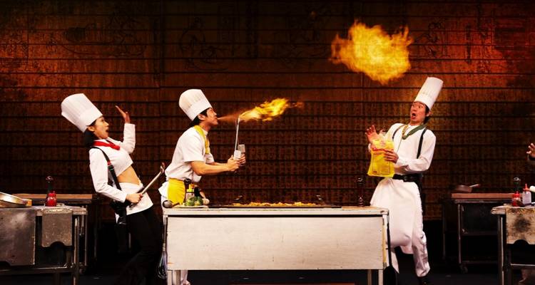 Chefs realizando un espectáculo culinario dramático con fuego.