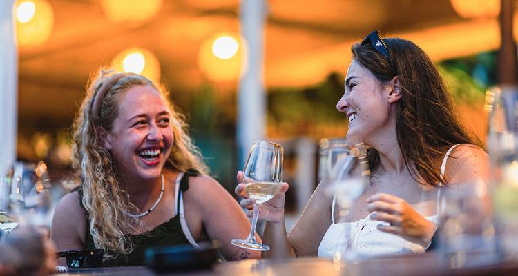 Deux femmes savourant des boissons et souriant lors d'un événement social.