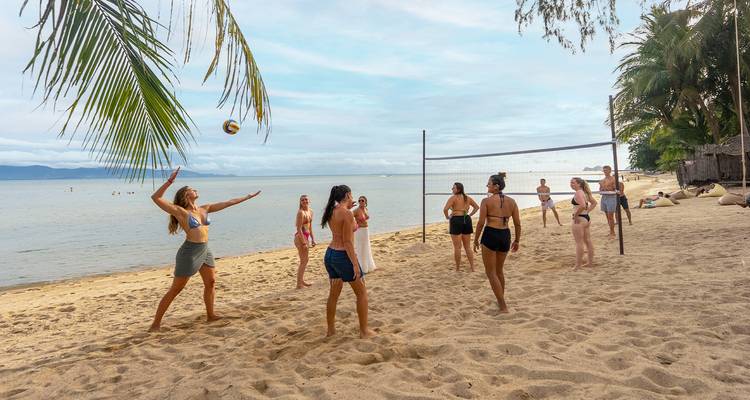 Groupe jouant au volley-ball sur une plage de sable.