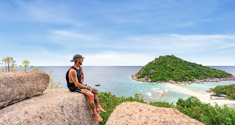Personne assise sur des rochers et contemplant la mer.