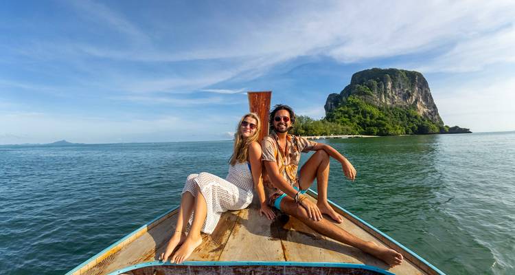 Couple assis sur un bateau avec vue panoramique sur l'océan et l'île.