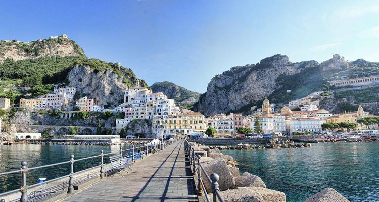 Pier die leidt naar het kleurrijke stadje Amalfi, omlijst door steile rotsachtige kliffen en heldere zee.