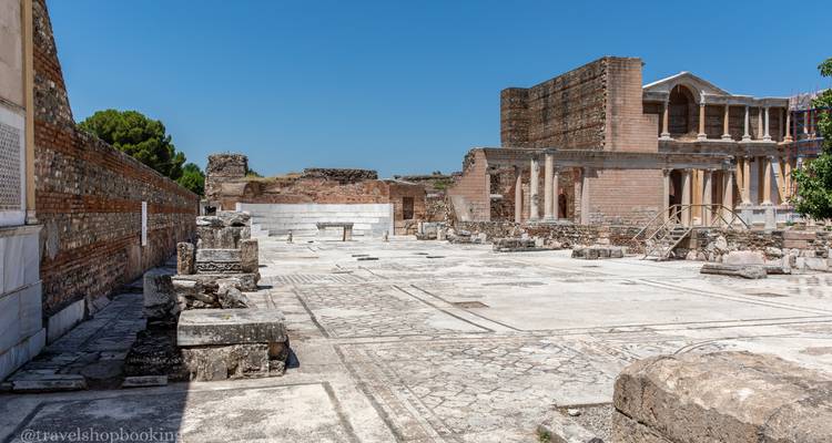 Cour pavée de pierres avec colonnes brisées et arches de la zone archéologique de Sardes sous un ciel dégagé