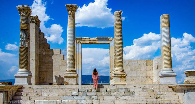 Visiteur debout entre les hautes colonnes de marbre de l'ancien temple de Laodicée avec des nuages brillants au-dessus