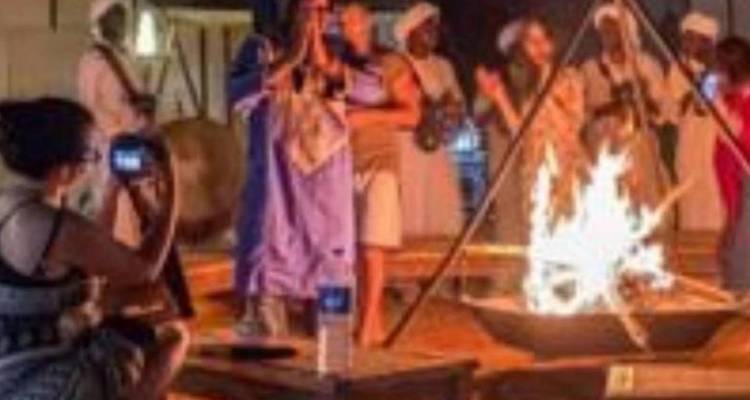 Image floue de personnes chantant et dansant autour d'un feu de camp.