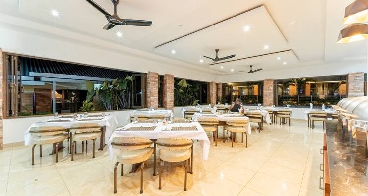 Restaurant interior with tables set for dining and an open view.