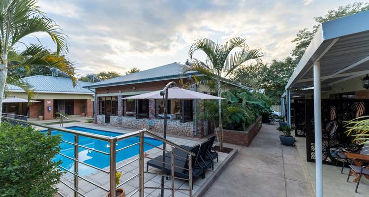 Outdoor pool area surrounded by a patio and vegetation.