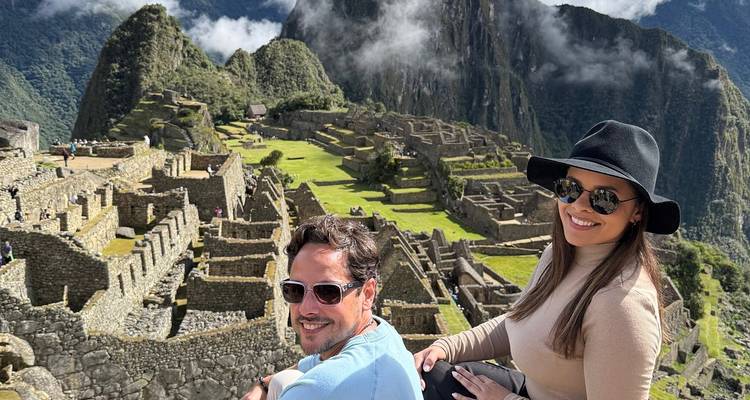 Pareja sentada con las ruinas de Machu Picchu de fondo.