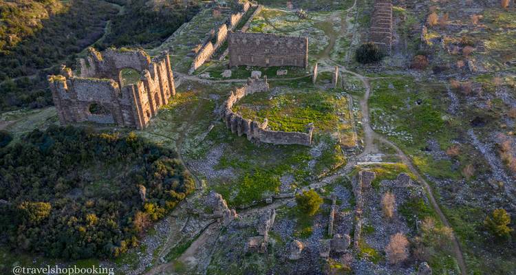 Vista aérea de extensas ruinas de piedra antigua dispersas por el campo verde.