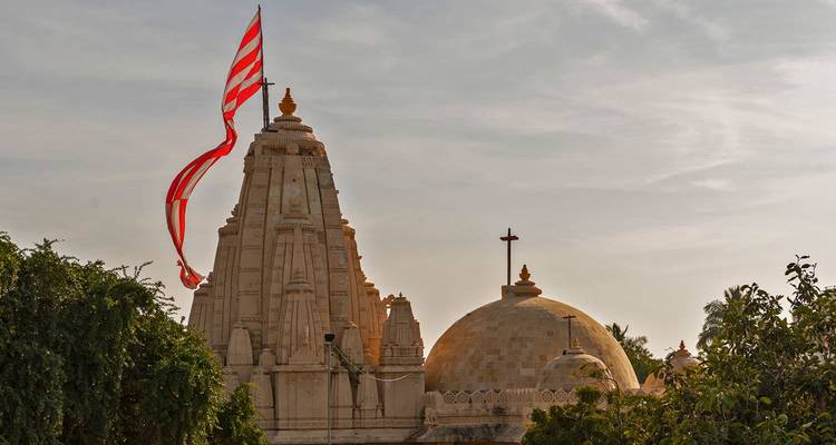Complejo de templos con una gran bandera ondeando, recortado contra el cielo del atardecer.