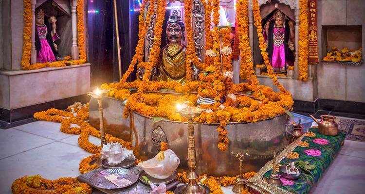 Santuario con guirnaldas de flores, múltiples deidades y ofrendas dentro de un templo.