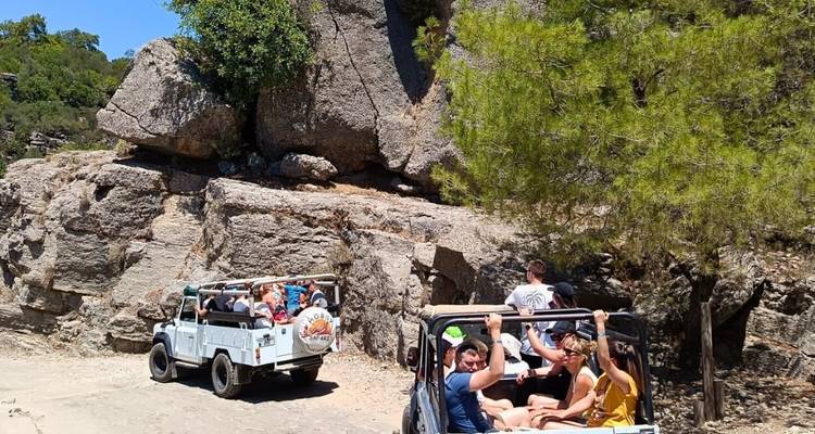 Groupe de personnes en safari en jeep à travers un terrain rocheux.