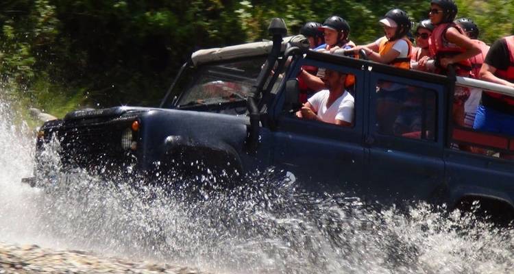 Jeep traversant un cours d'eau avec des passagers à bord.