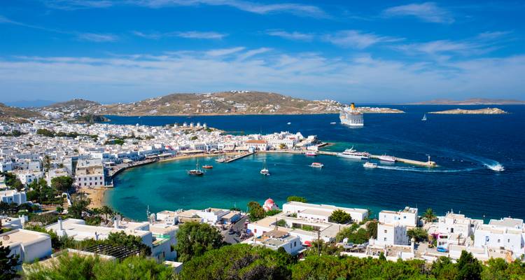 Vista del puerto de Mykonos con embarcaciones y un crucero al fondo.