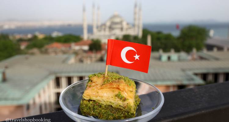 Stück Pistazien-Baklava mit türkischer Flagge vor verschwommener Moschee-Skyline