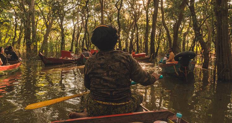 Une personne ramant dans un bateau sur une voie navigable en forêt.
