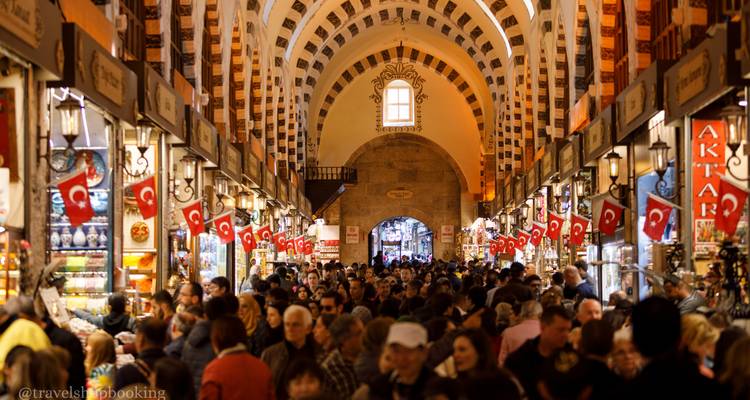 Crowded interior of Istanbul's Spice Bazaar lined with Turkish flags and arched ceiling