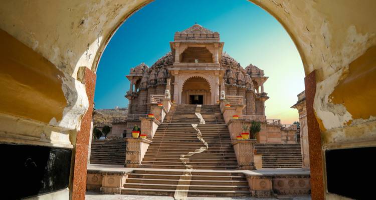 Prächtiger Tempel mit einer großen Treppe und kunstvollen Schnitzereien, gesehen durch einen gewölbten Eingang.
