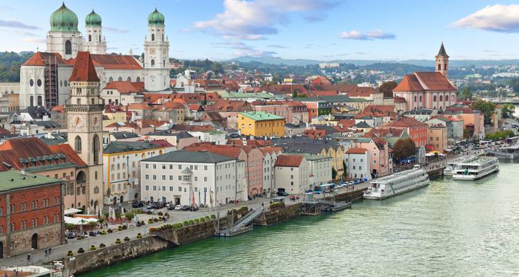 A panoramic view of a river city with colorful buildings and churches.