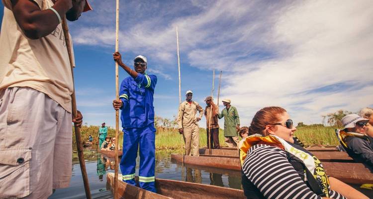 Menschen bei einer Kanu-Safari auf einem Wasserlauf bei klarem Himmel.