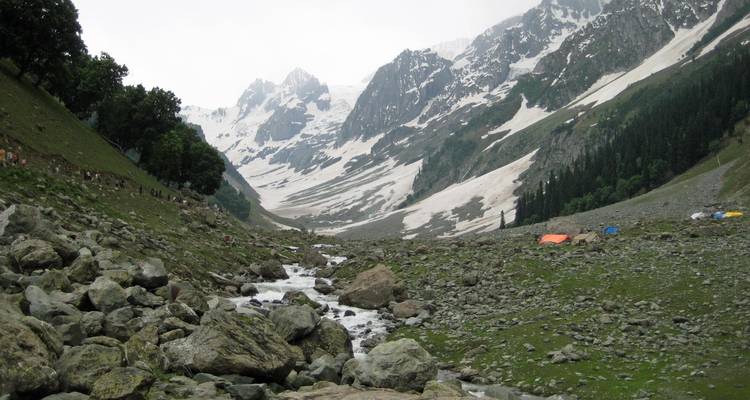 Besneeuwde bergen met een beek die door een vallei stroomt.