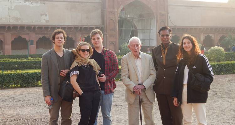 Group of people posing in front of a historical building in the evening.