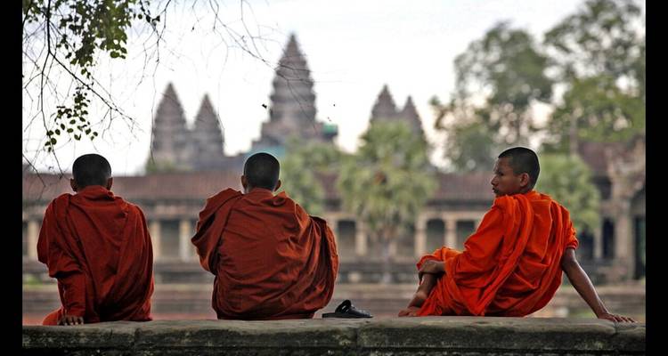 Mönche in orangefarbenen Gewändern, die bei Angkor Wat sitzen