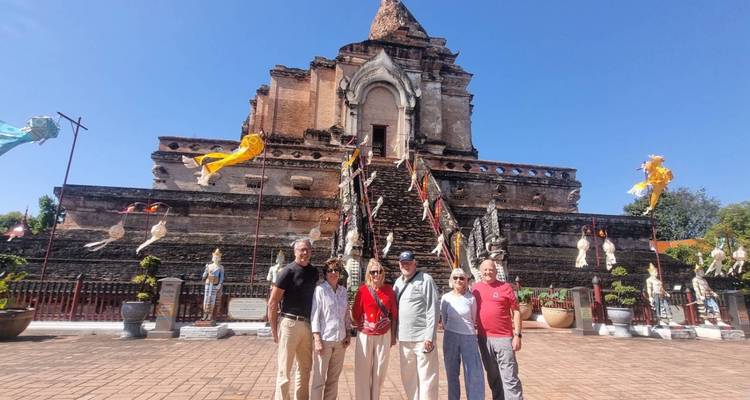 Los visitantes se encuentran ante las antiguas ruinas de ladrillo de la estupa de Wat Chedi Luang bajo cielos azules.