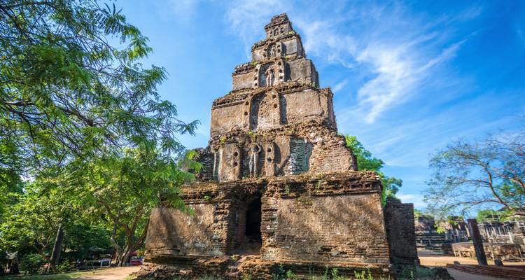 Ancient brick and stucco temple ruin with trees in the background