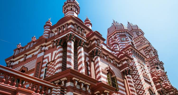 Colorful red and white mosque architecture against a blue sky.