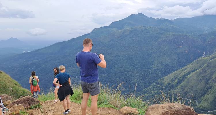Hikers taking photos on a scenic mountainous viewpoint.