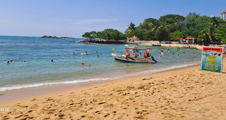 Beach with people swimming and a boat in the water.