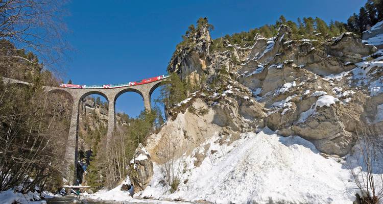 Grand viaduc dans un paysage rocheux et enneigé