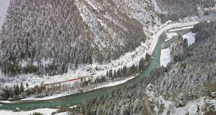 Vue aérienne d'une rivière serpentant à travers une forêt enneigée.