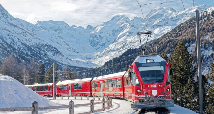 Train rouge traversant les montagnes enneigées en Suisse.